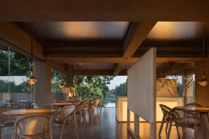 Cozy restaurant interior with wooden tables and chairs, potted plants, and a modern design