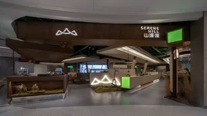 A modern hotel lobby with a high ceiling, wooden walls, and potted plants adding greenery to the space