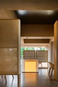 A warm and inviting living space with a glass wall separating two rooms, featuring a wooden table and comfortable seating arrangement, with natural light streaming through the glass wall