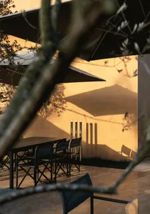 A wooden table surrounded by black metal chairs under an umbrella in a relaxed outdoor dining area