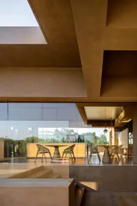 A warm and inviting living room with a large window, chairs, and a dining table, surrounded by natural light