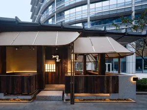 Warm and inviting Asian restaurant with wooden walls and floors, featuring a dining area with tables, chairs, and potted plants