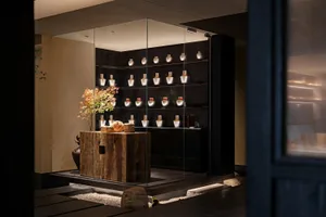 A large glass display case in an interior design showroom contains thirteen vases of various sizes and shapes, creating an elegant and sophisticated atmosphere