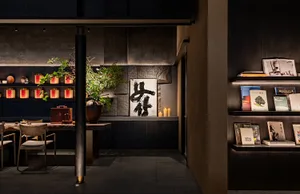 Cozy Asian-inspired living space with a black and white theme, featuring a dining table, bookshelf, and potted plants