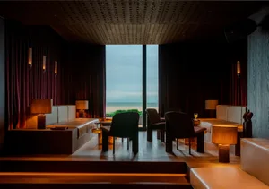 Sophisticated living space with ocean view, chairs, and dining table, surrounded by natural light and tranquil atmosphere