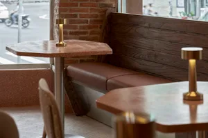 Cozy restaurant interior with wooden tables, chairs, and a bench, creating a warm atmosphere for social gatherings or casual meals