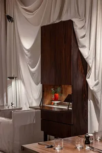 a modern kitchen with a wooden cabinet, sink, and two chairs, suggesting a cozy and functional living space