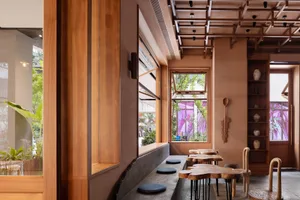 Warm and inviting restaurant interior with wooden walls and floors, natural light from windows, and seating areas