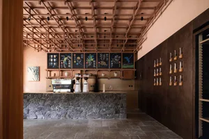 A cozy coffee shop interior with a stone wall, wooden elements, and espresso machines, surrounded by cups and bottles, inviting a pleasant atmosphere