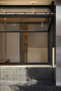 Empty modern living space with a large window, tiled walls, cabinets, and countertops, flooded with sunlight
