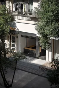 Exterior view of a rustic cafe with a large window, two benches, and a dining table in a relaxed and inviting atmosphere