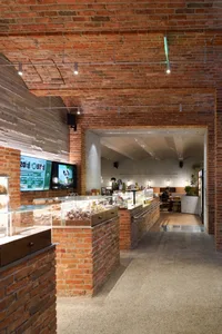 Inviting cafe interior with a brick wall, glass display case, and people seated at tables