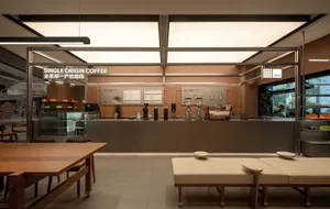 A coffee shop interior with a counter featuring coffee equipment and multiple chairs for seating, creating a welcoming atmosphere