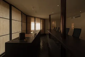 A restaurant dining area with a large wooden table surrounded by multiple chairs, creating a cozy and inviting atmosphere for guests to gather and enjoy their meals
