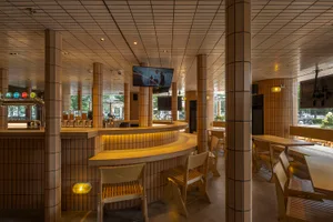 A casual bar area with a counter and three chairs, a TV screen above, and a focus on socializing and enjoying food or drinks