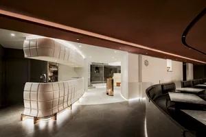 Open living area with white walls and flooring, featuring a combined kitchen, dining room, and living room with comfortable seating and a dining table