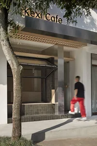 A modern building with a glass facade, natural light, and a man walking by in the foreground