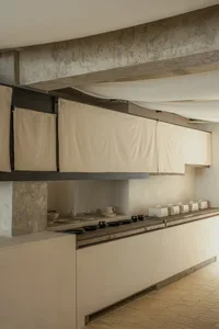 Empty kitchen with white walls and cabinets, featuring bowls, cups, and vases on countertops in a clean and minimalistic atmosphere