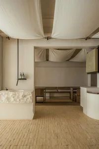 Empty minimalist bathroom with white walls and wooden floors, featuring two sinks on either side of the room