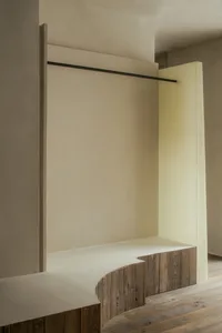 Empty room with a white wall, a wooden bench, and a doorway, giving a clean and minimalist appearance