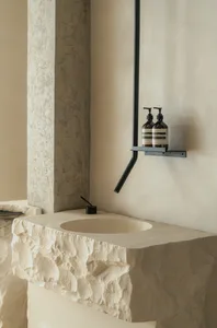 Minimalist bathroom with a wall-mounted soap dispenser, sink, and two bottles of soap on the countertop