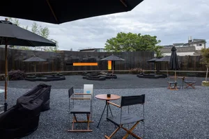 A relaxed outdoor patio area with wicker chairs, dining tables, and umbrellas, perfect for casual dining or conversation