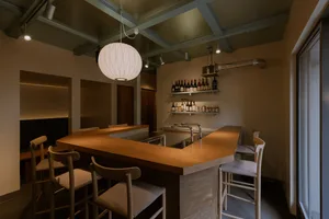 Warm and inviting restaurant space with wooden floors and walls, featuring a dining table and chairs, wine bottles, and wine glasses