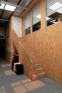 A wooden staircase in a building with a doorway and window, creating a warm and inviting atmosphere