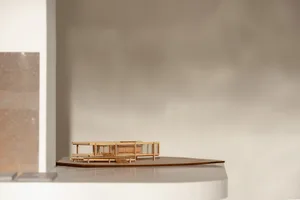 A wooden architectural model of a modern building on display, showcasing clean lines, windows, doors, and structural components, with highlighted intricate details and craftsmanship