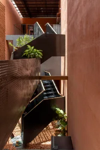 A calm and inviting staircase with wooden steps and a black railing, flanked by two potted plants