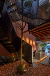 A well-lit interior space with a staircase, black railing, and two potted plants, suggesting a modern and natural design