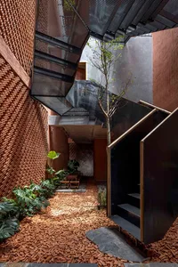 A building with a brick exterior, black railings on two sets of stairs, and a bench near the bottom stairs
