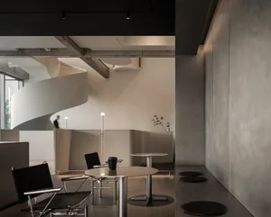 Modern lobby with a spiral staircase, chairs, and a dining table, set in a large open space