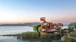 A serene and inviting modern building with a circular structure situated on a body of water, featuring an open area with ample natural light through windows