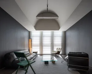Sleek and contemporary living room with a large couch, chair, dining table, and two chairs, emphasizing openness and functionality
