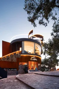 A modern building with a glass dome and red brick exterior, featuring a spacious lobby with natural light, potted plants, and seating areas