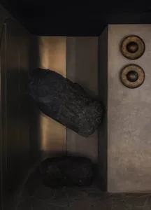 A dark room with two large rocks and three smaller rocks, along with four round objects, scattered throughout the space