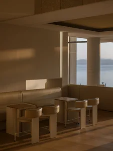 A warm and inviting cafe with a large window overlooking the ocean, featuring comfortable seating and natural light