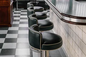 A modern bar with multiple black leather stools and a well-lit counter, creating an inviting atmosphere for customers