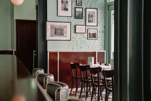 A warm and inviting dining area with a long wooden table and multiple chairs, surrounded by framed pictures on the walls