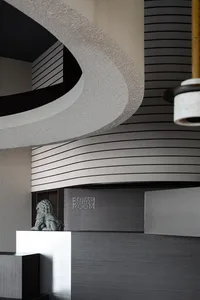 A modern room with a curved ceiling, grey walls, and two large hanging lights, creating a bright and inviting atmosphere