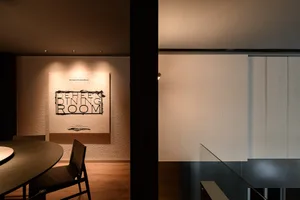 A modern dining room with a large table, chairs, a couch, and white walls, creating a clean and bright ambiance