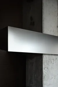 A dimly lit interior space with a large metal wall mounted on a concrete block, featuring a minimalist and contemporary style