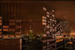Modern restaurant interior with brick walls, tables, chairs, and potted plants, creating a warm and inviting atmosphere