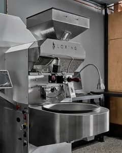 Industrial kitchen with a large silver machine, bowls on the countertop, and a sink at the far end of the room