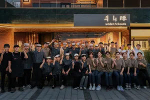 A group of people gathered in front of an Asian-themed restaurant, smiling and posing for a photo