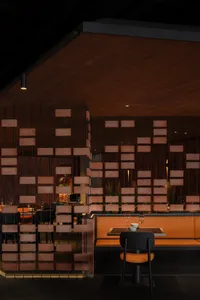 A well-lit restaurant interior with brick walls, wooden elements, and multiple chairs, featuring wine glasses on display