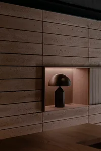 A cozy living space with a wooden table and a lamp with a black base and white shade, set against a darker background