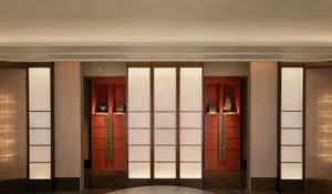 A brightly lit hallway with Asian-style doors, decorative vases, and books, creating a warm and inviting atmosphere