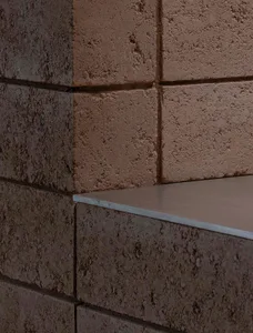 A serene outdoor space with a brick wall and a built-in concrete bench, inviting relaxation and contemplation
